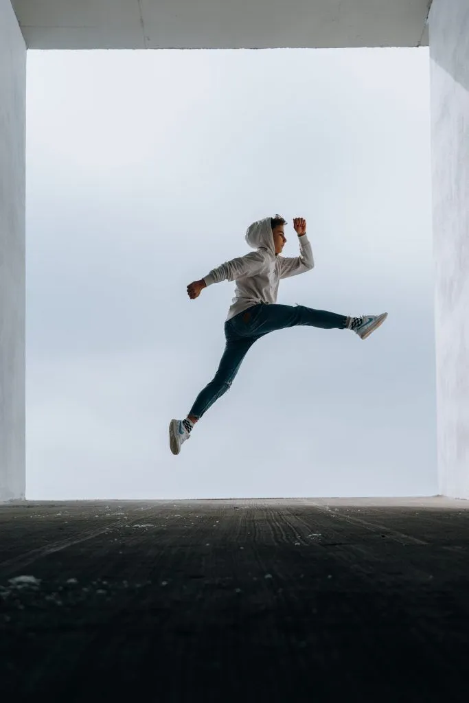 boy jumping framed by large window