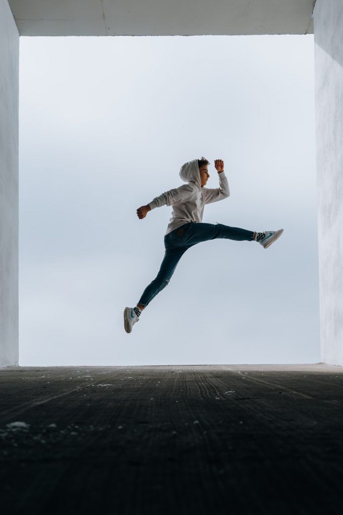 boy jumping framed by large window