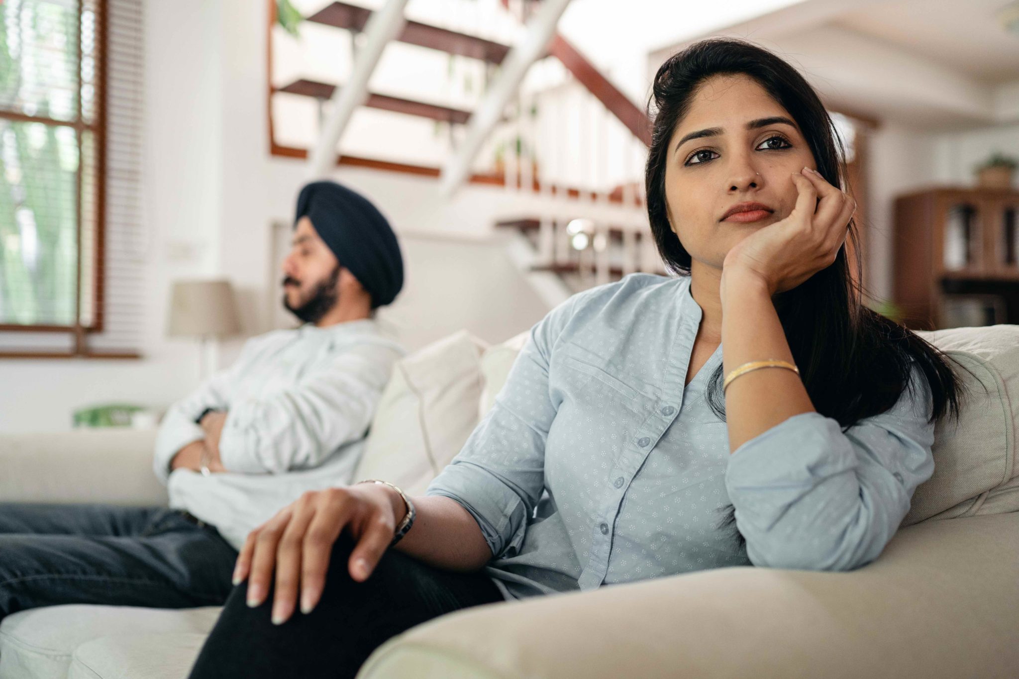 couple sitting on couch staring in opposite directions