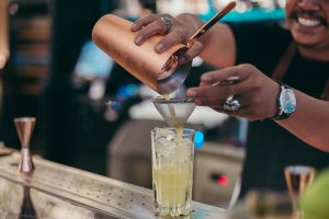 smiling bartender pouring drink into glass