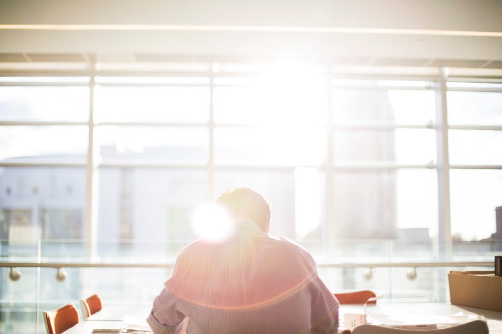 long hours and risky drinking man at a desk in sunbeam