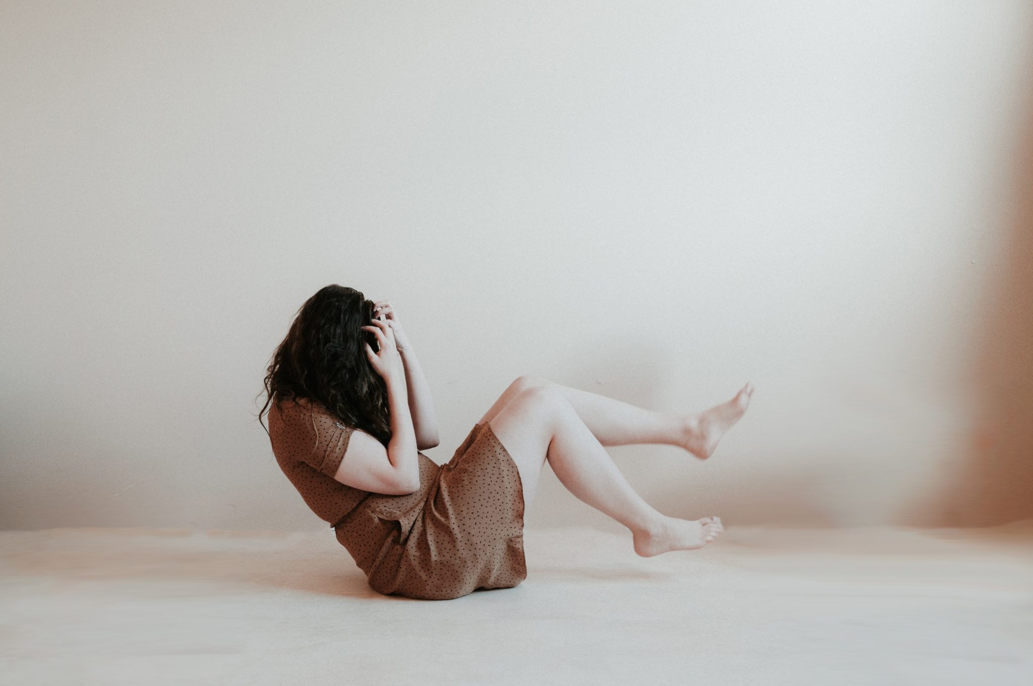 woman sitting on the floor clutching her head, hangover anxiety