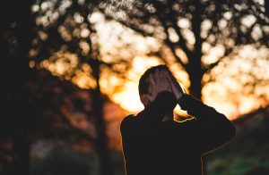 man standing in forest with headache, alcohol and stress