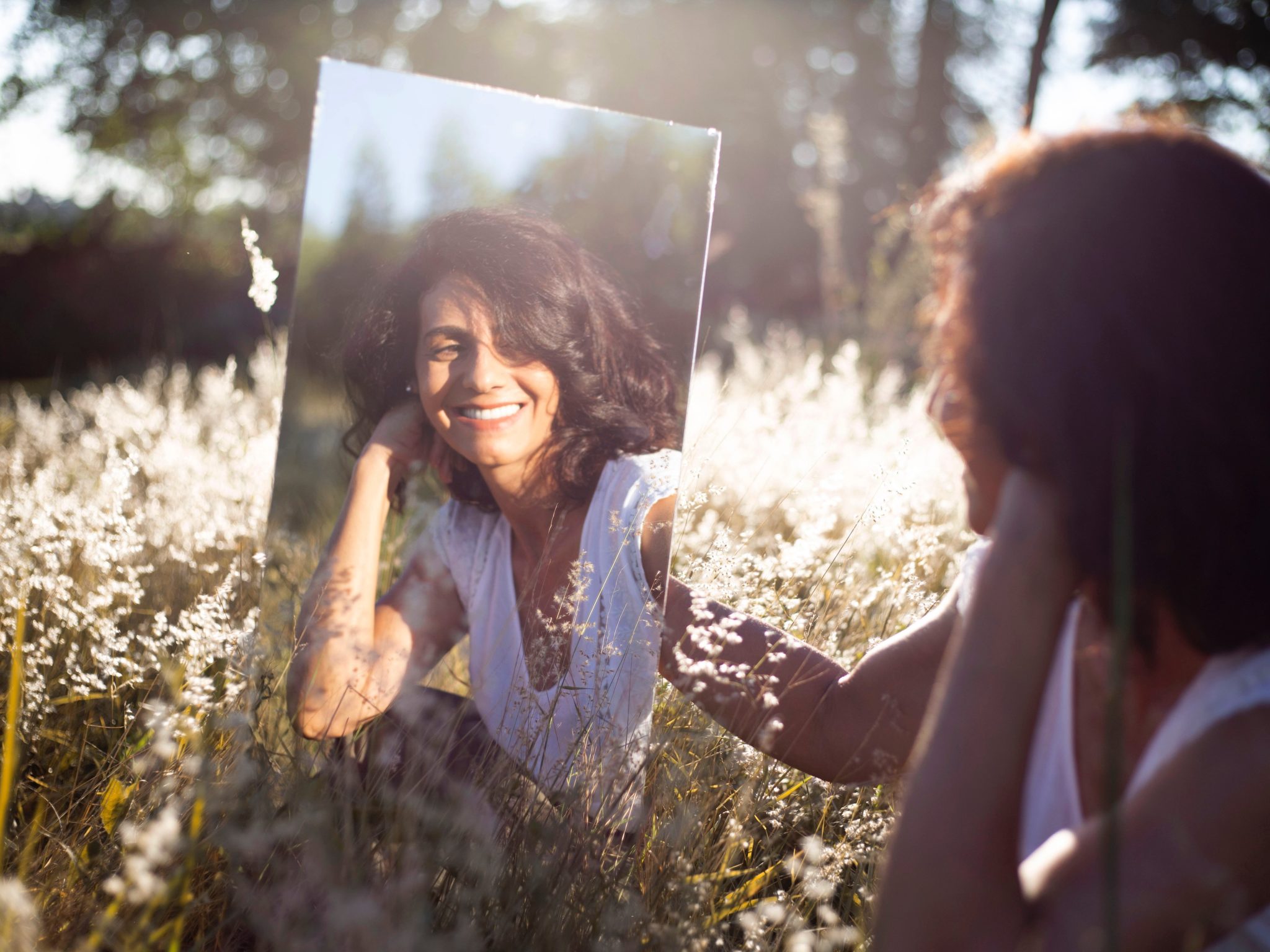 woman looking in mirror, effects of alcohol on skin