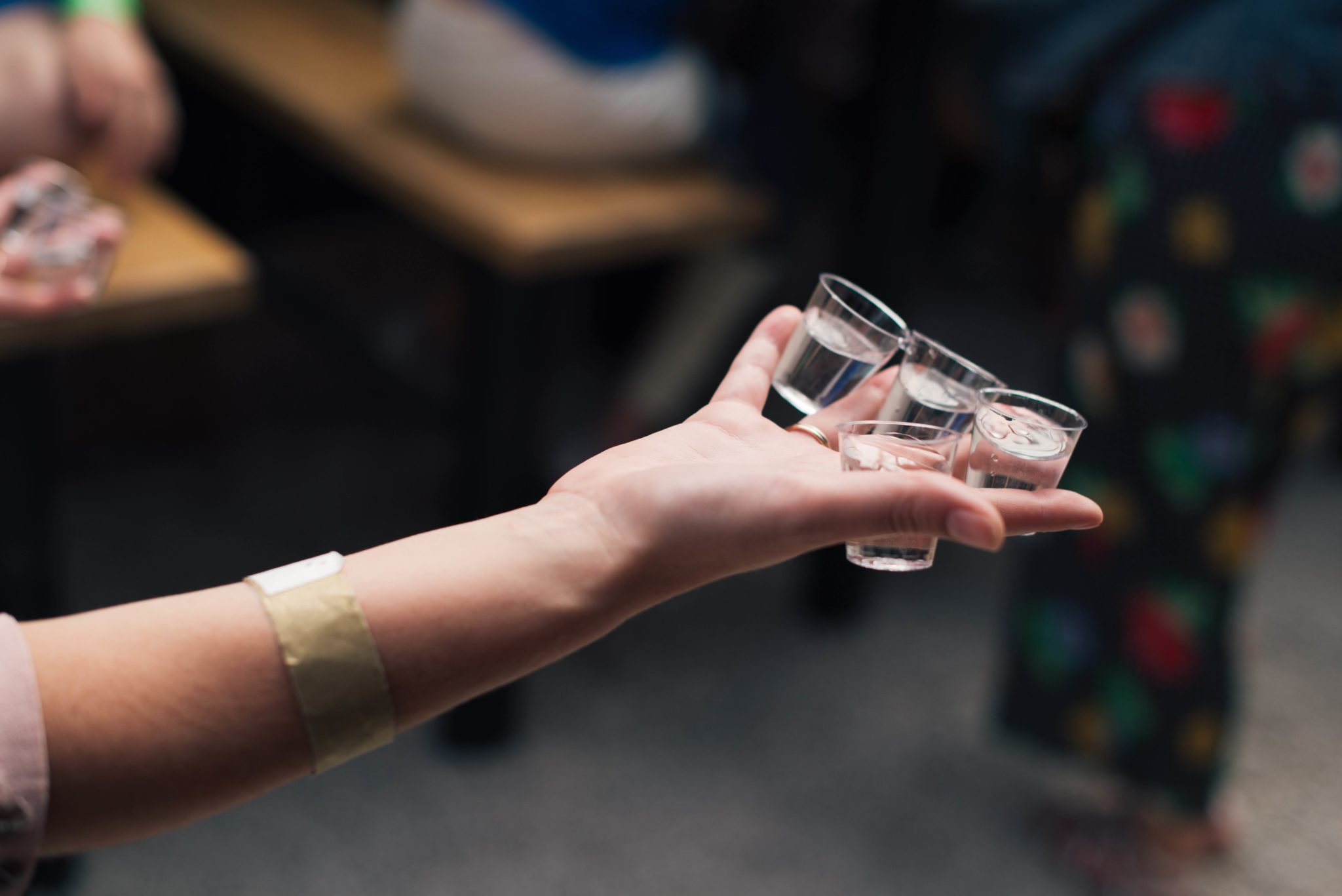 person holding several shots, drinking vodka every day