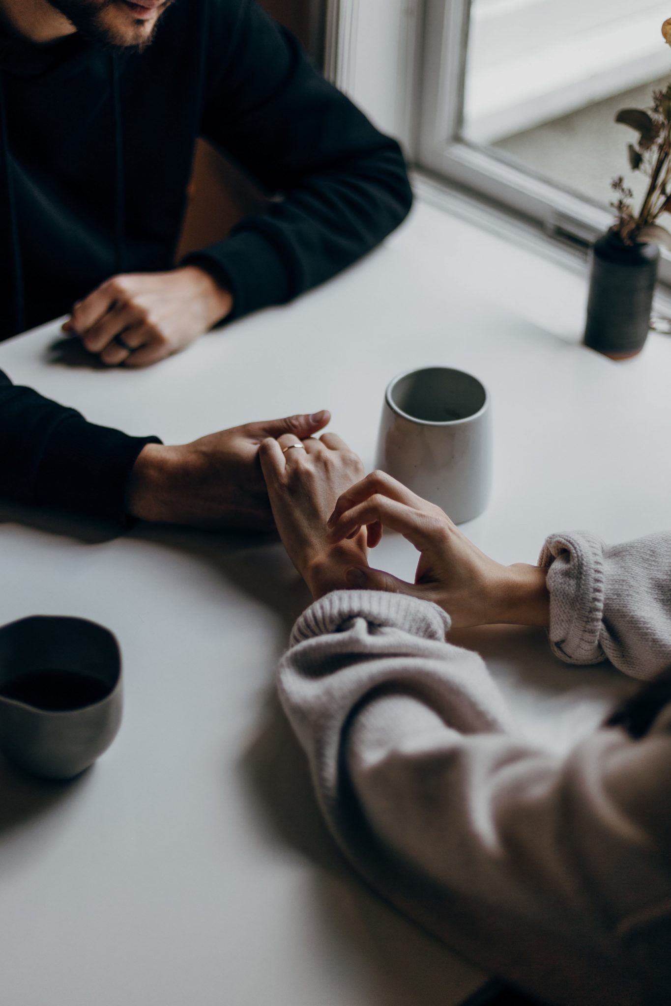 couple holding hands over coffee, talk to your partner about your addiction