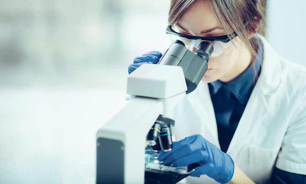 researcher looking through microscope