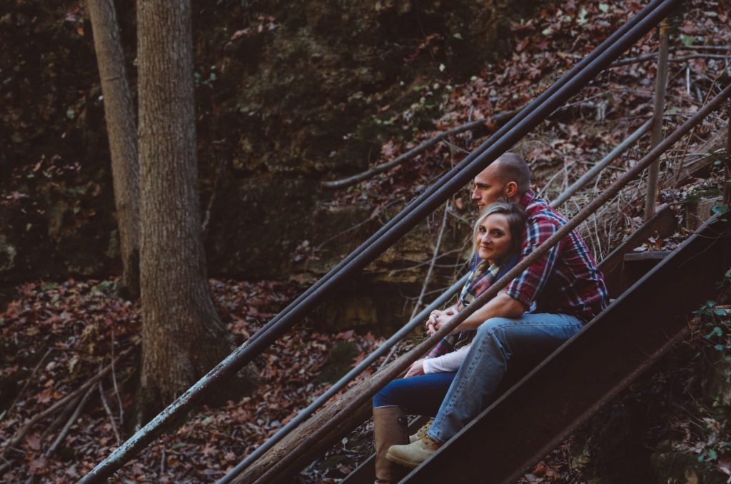 man embracing woman on steps in the woods