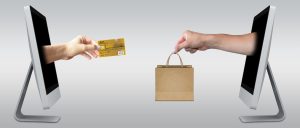 credit card and shopping bags exchanged by hands coming out of computer screens
