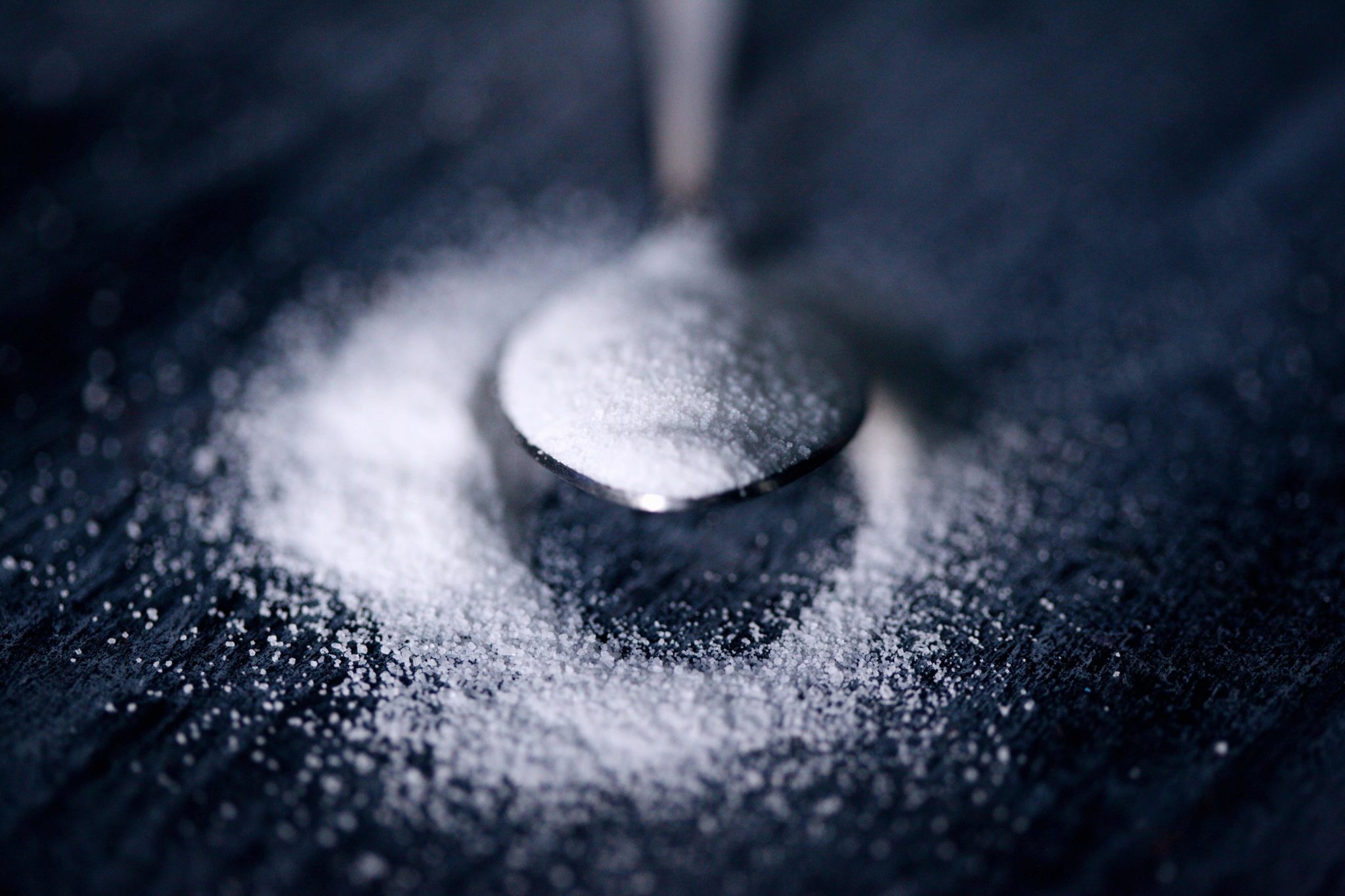 spoon holding white powder on dark background