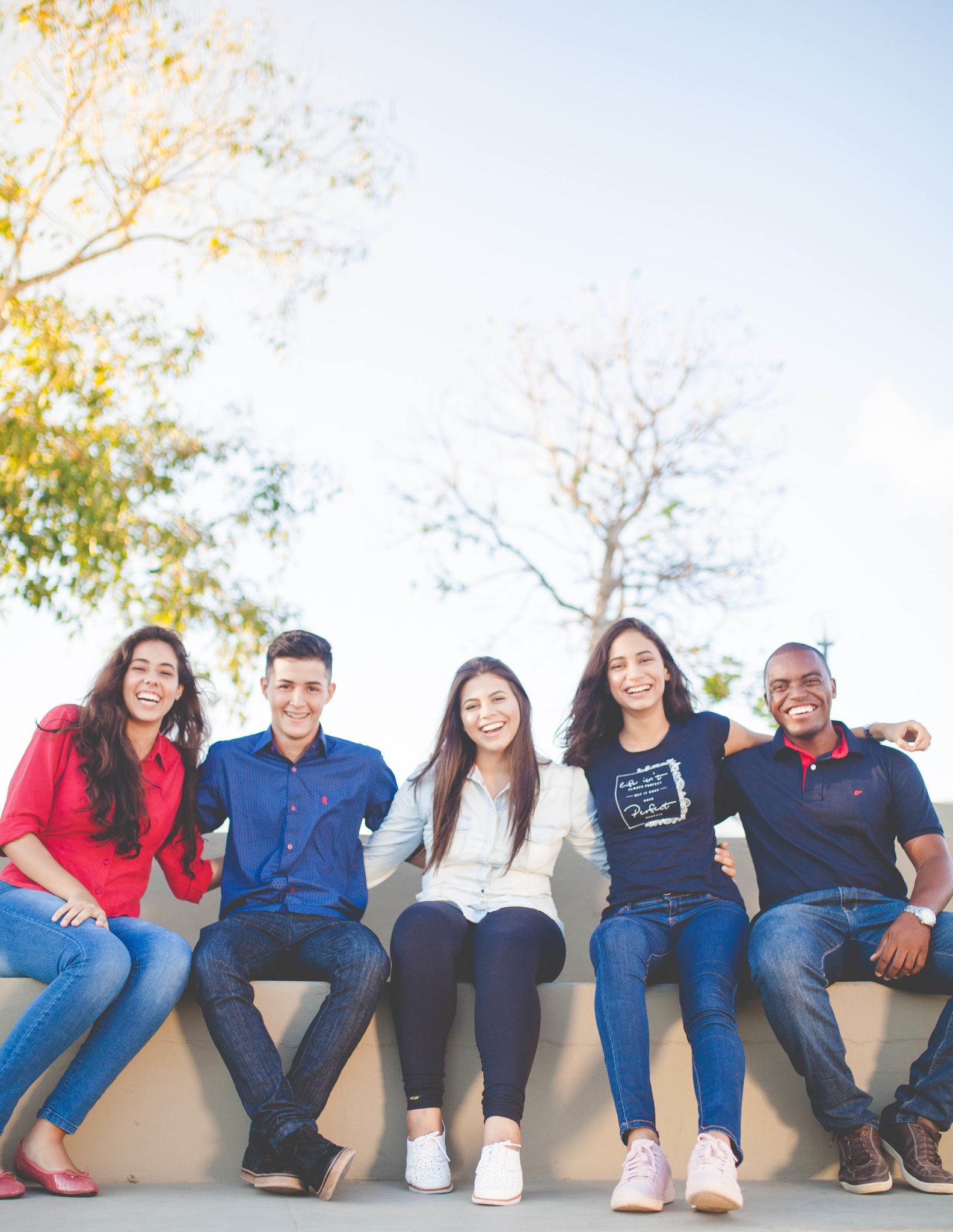 smiling college students sitting on a wall