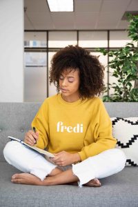 woman writing in journal on couch