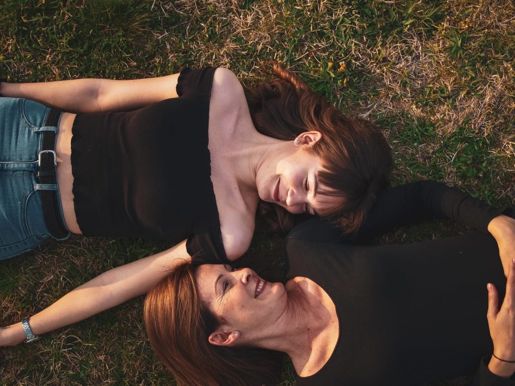 mother and adult daughter lying together on grass