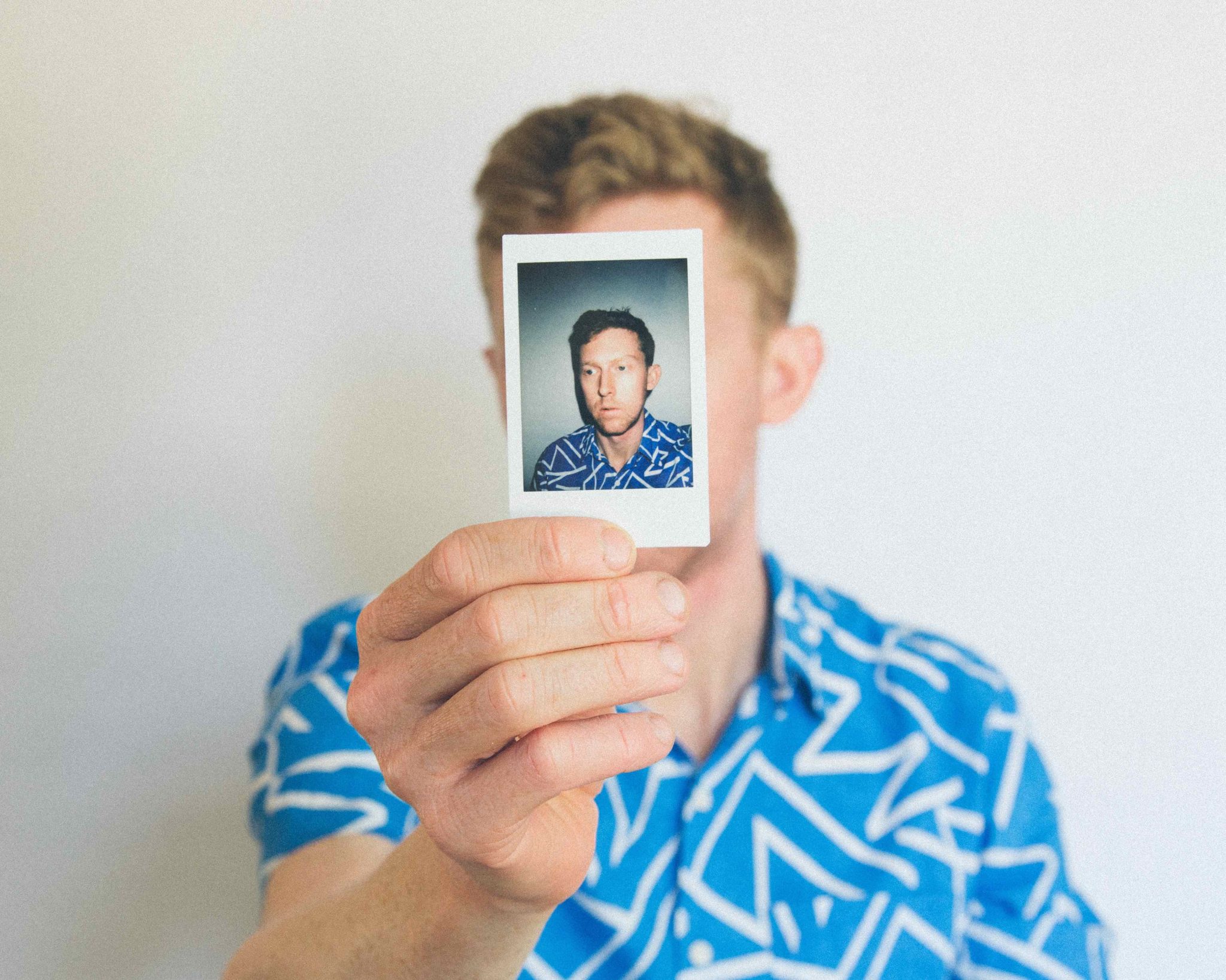 man holding a polaroid of himself