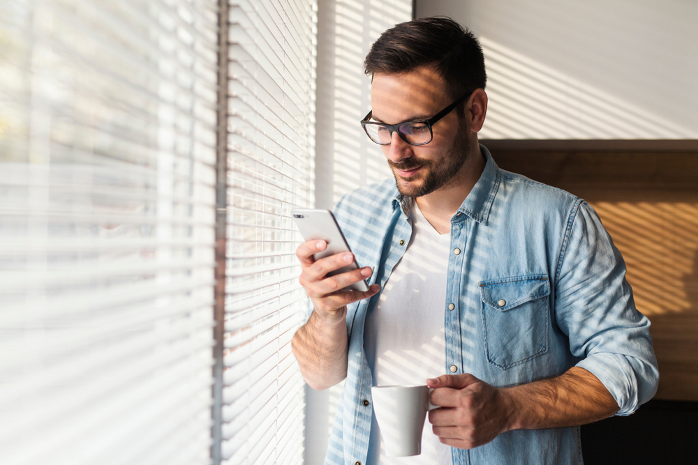 man standing by window using a telemedicine app
