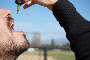 man with a dropper held over his mouth