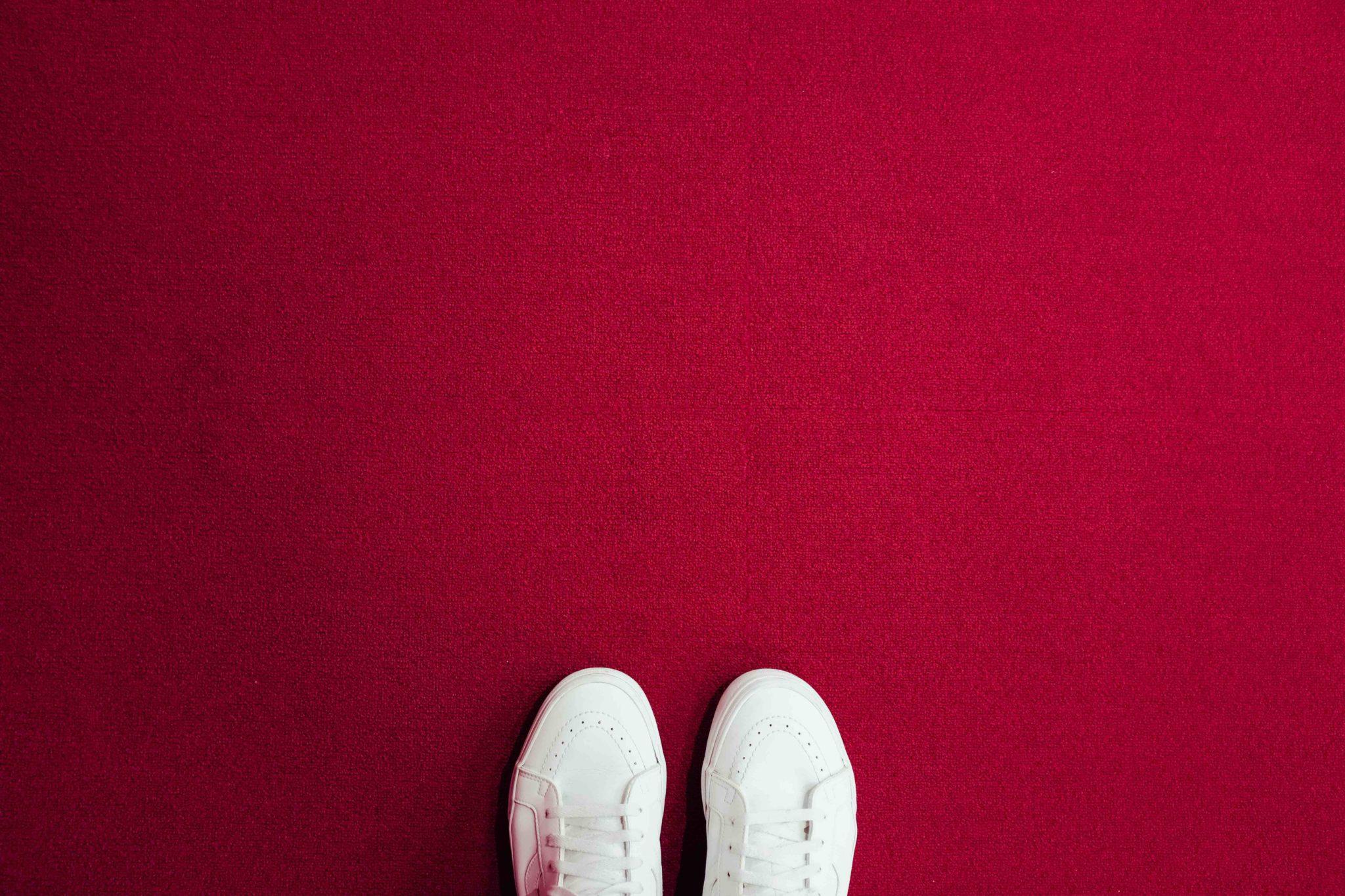 feet in white shoes on red carpet