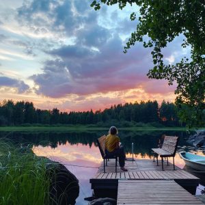 woman sitting on a dock by a lake on a beautiful july evening