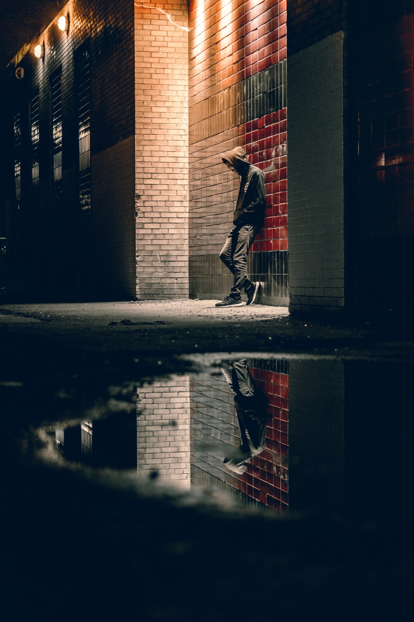 man leaning against a wall at night