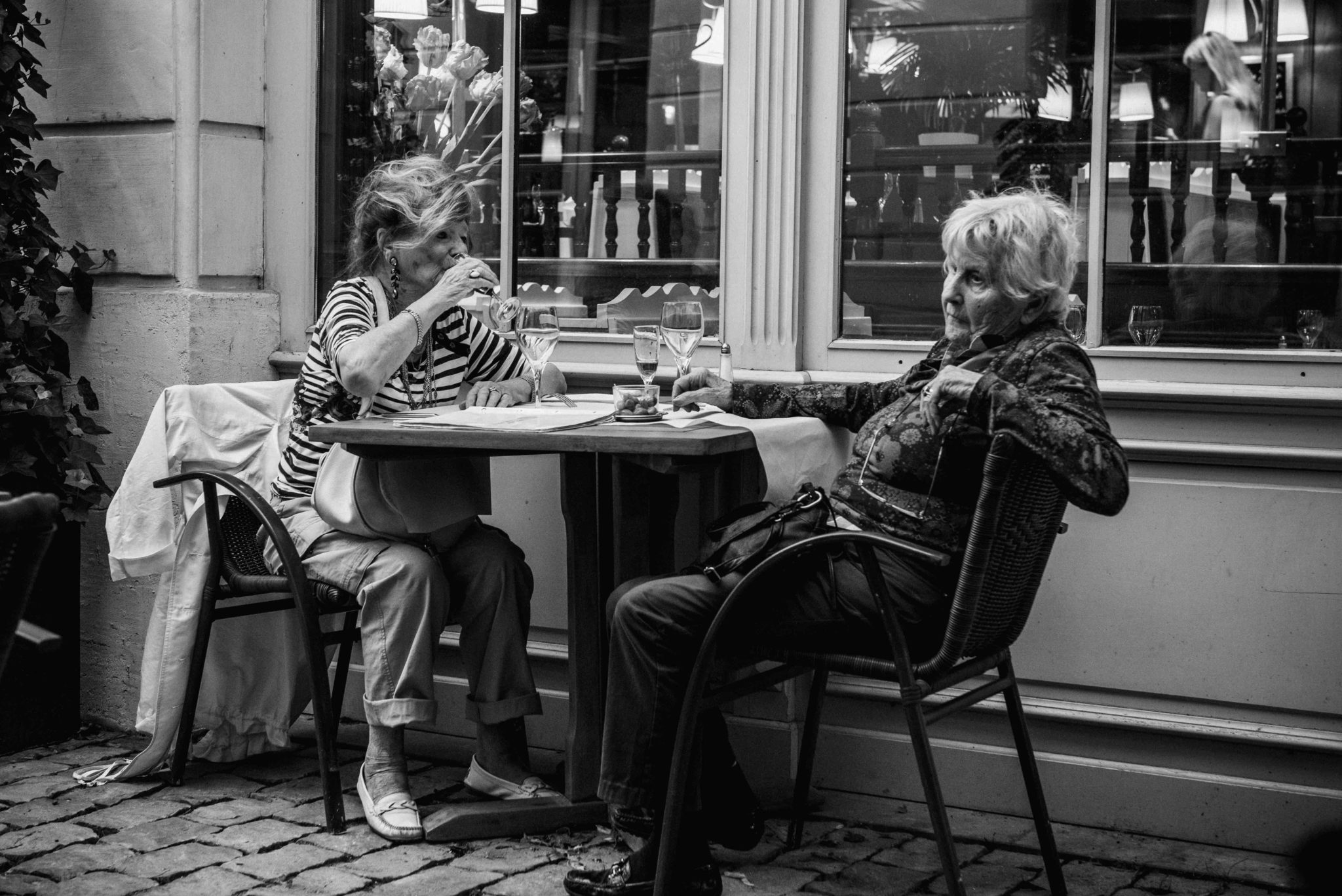 two women drinking wine at an outdoor cafe