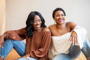 two well-dressed women sitting together and laughing