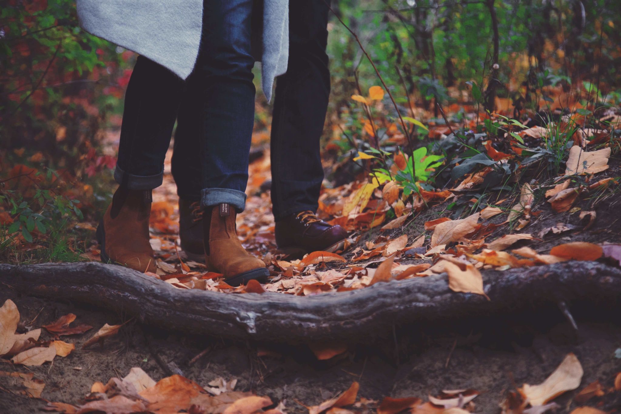 two pairs of boots walking on a forest path together