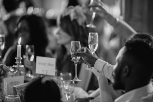 black and white photo of people raising glasses at a wedding