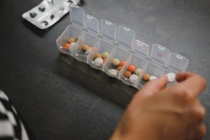 person dividing up medications into a weekly pill box