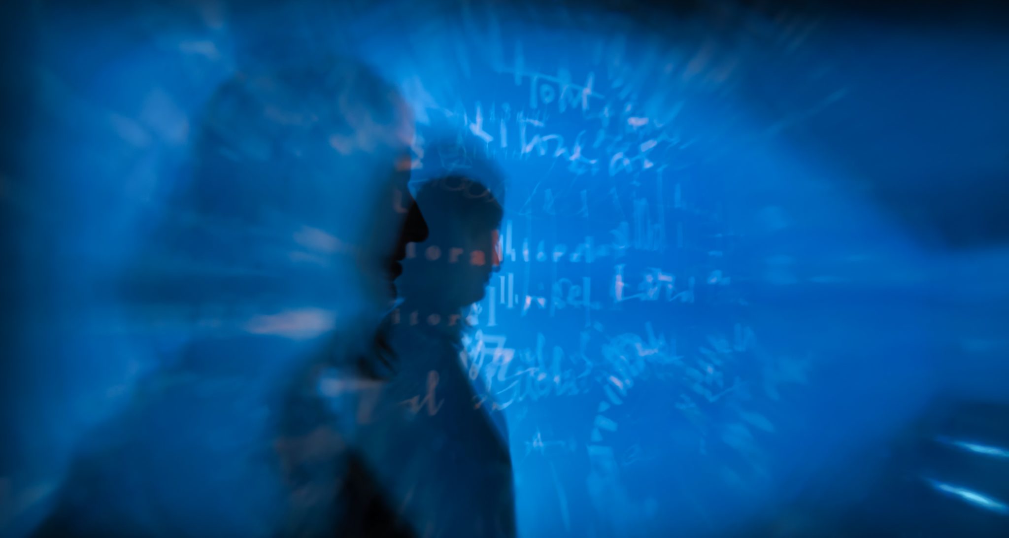 blurry blue silhouette of a person with abstract writing in the background