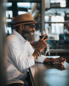 bearded man holding glass of wine and smiling