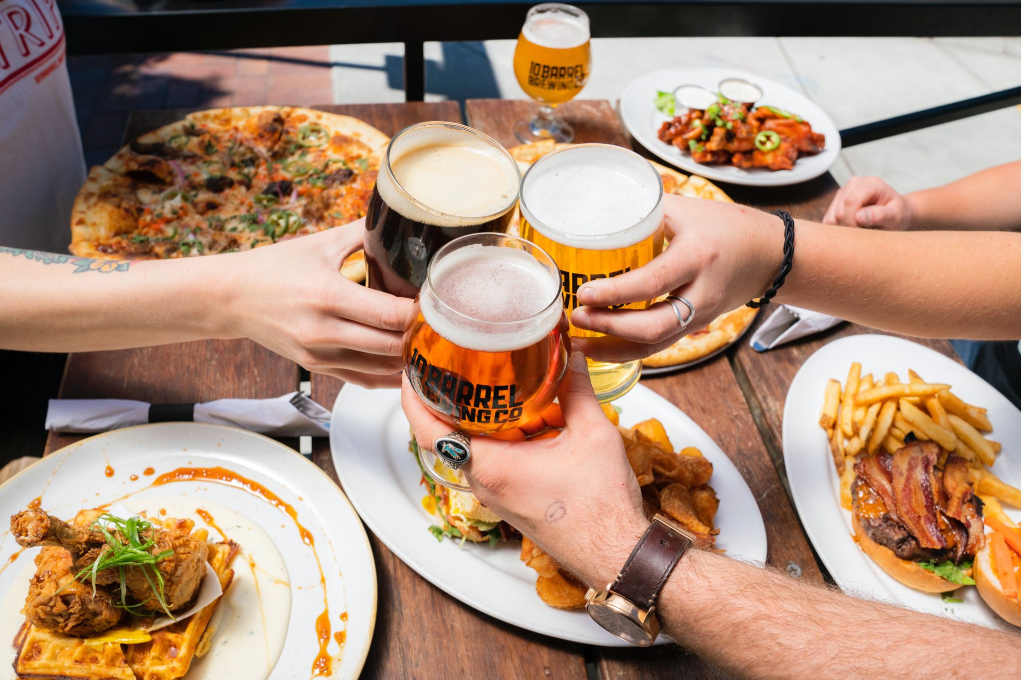 several people toasting beer glasses over a cholesterol heavy meal