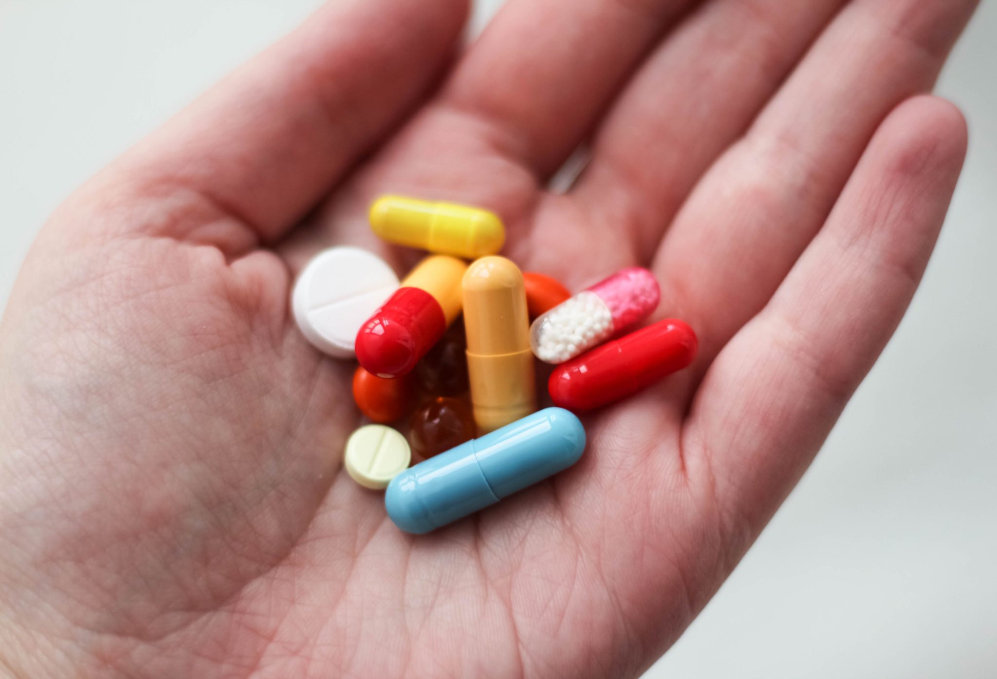 hand holding several brightly colored pills