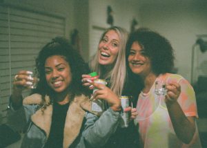 3 young women in a grainy photo holding drinks