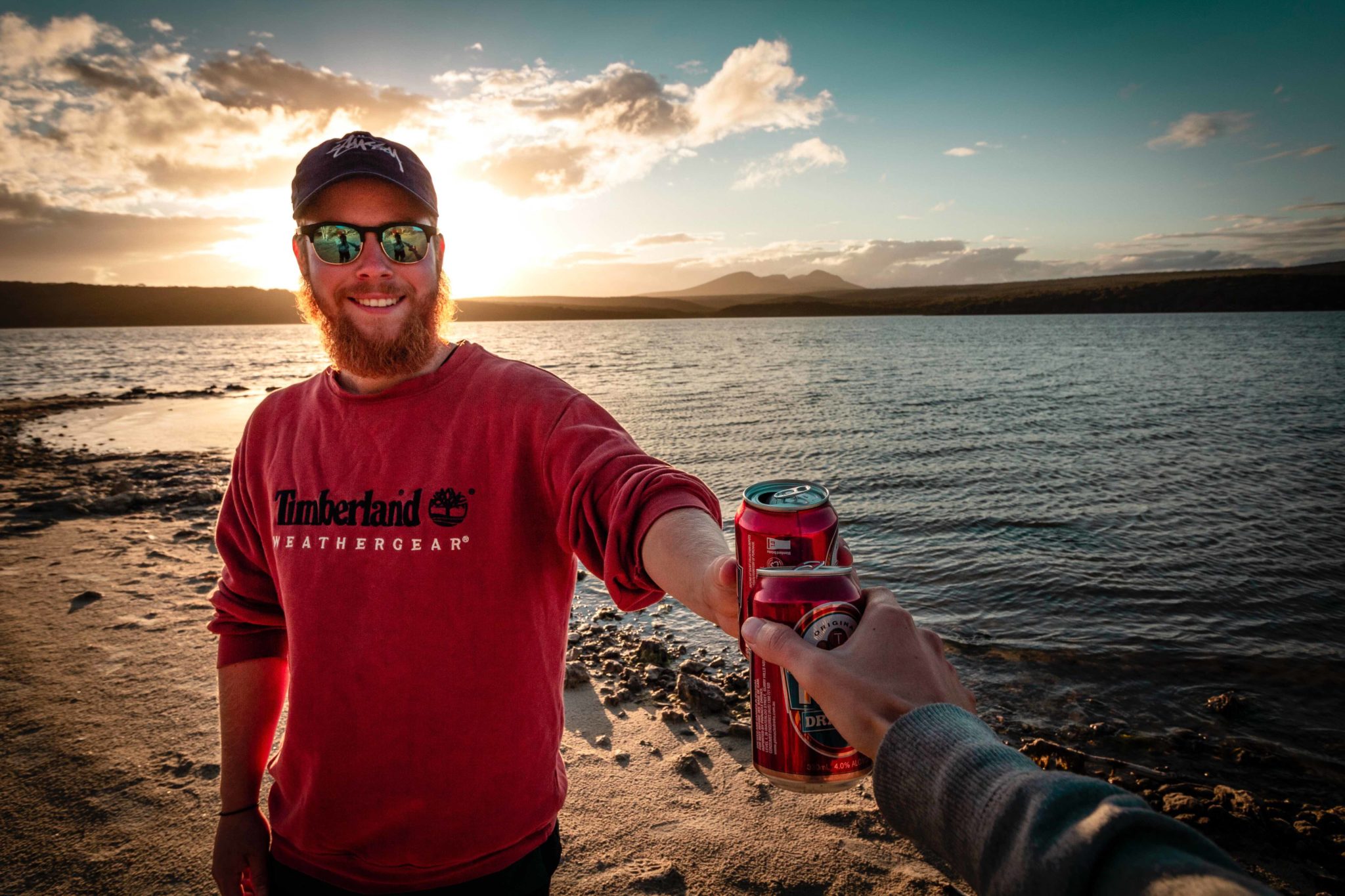 smiling man in red sweatshirt with beer