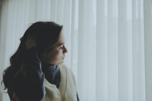 woman standing by curtain feeling anxious