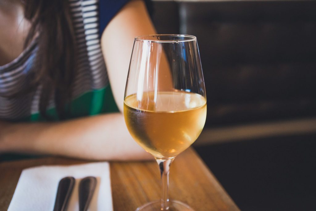 glass of wine on table, person sitting nearby