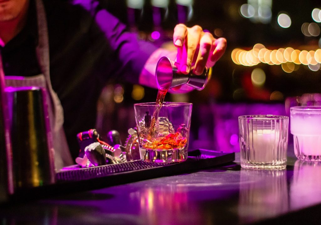 hand pouring a cocktail purple light