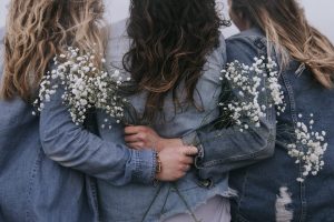 three women holding flowers with their backs to the camera