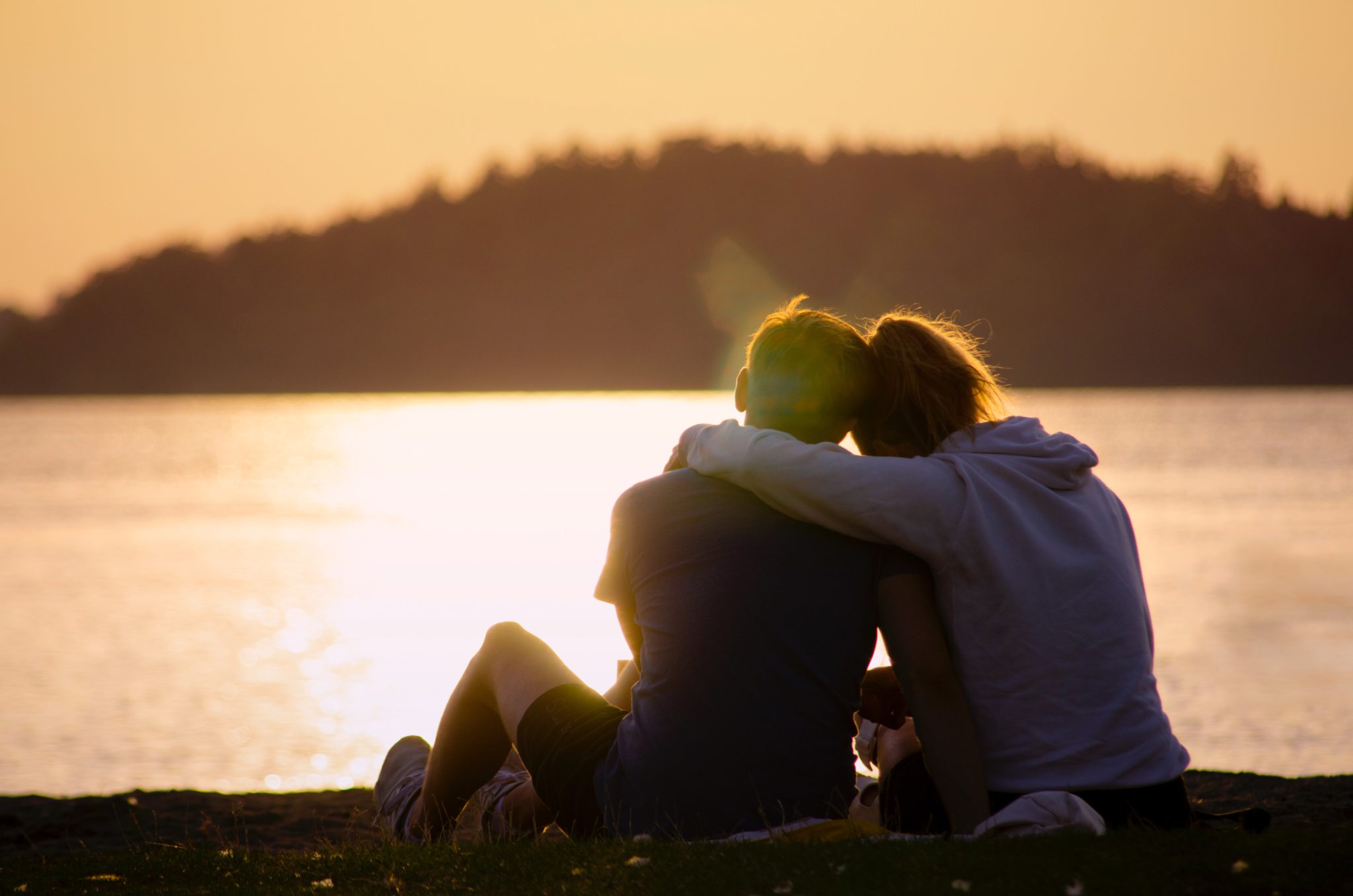 two people hugging while watching a sunset