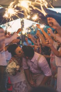 bride and groom kissing beneath a line of relatives holding sparklers