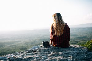 woman sitting on rock overlooking landscape