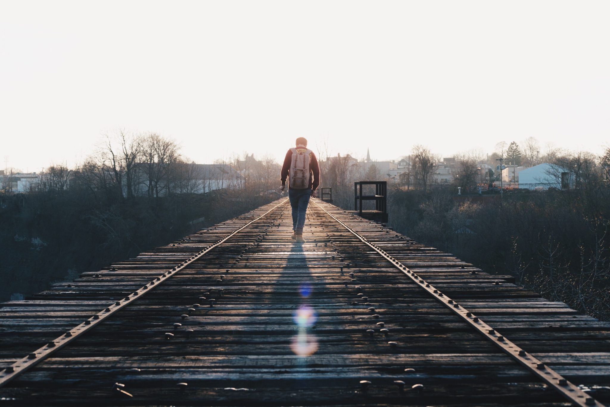 man walking down railroad tracks
