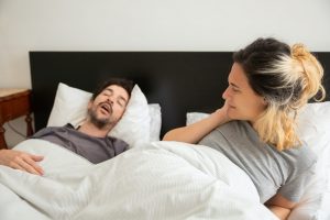 woman holding her ears while her partner snores