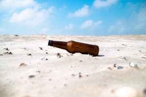 empty beer bottle lying on dry sand