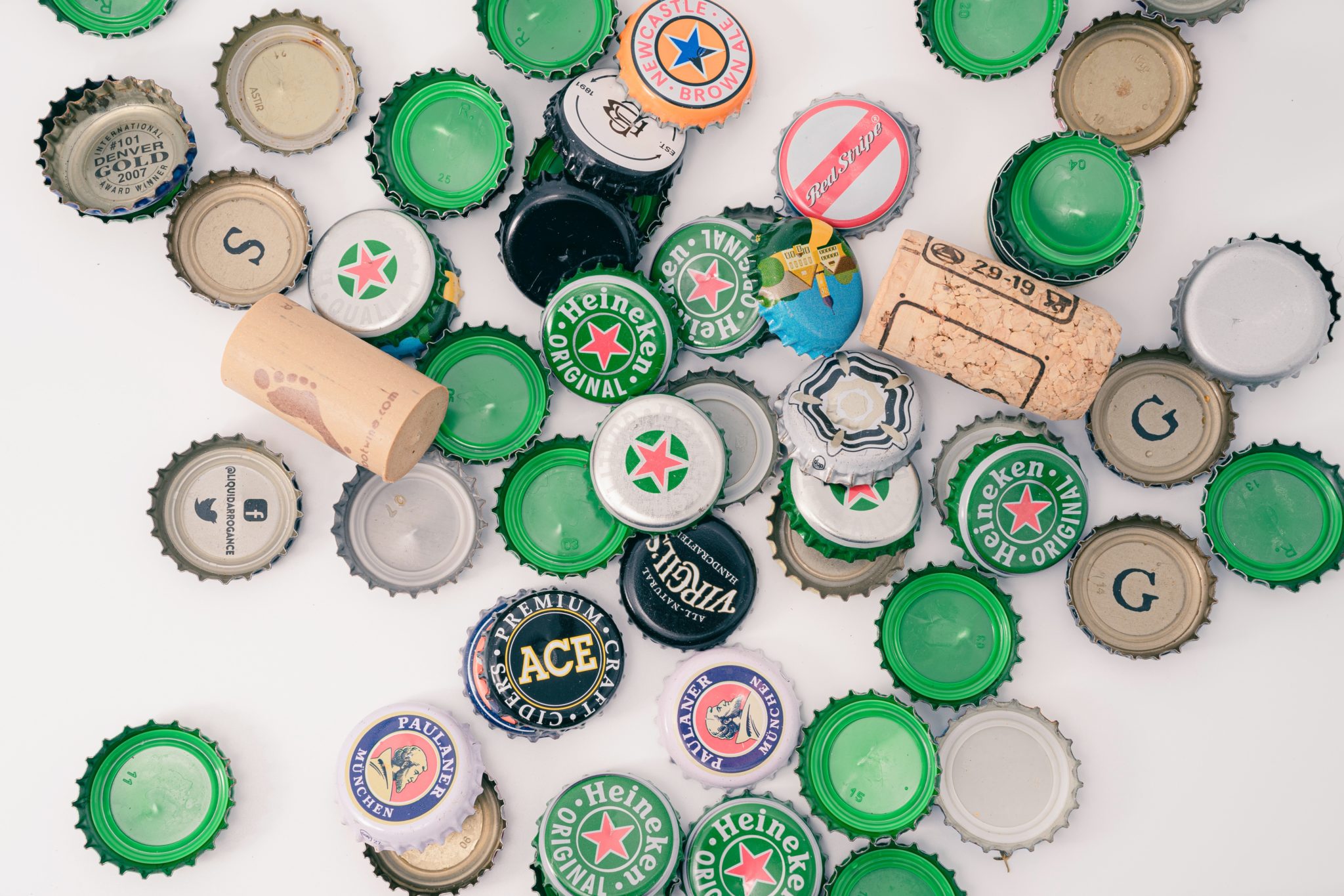 assorted beer bottle caps and wine corks on white background