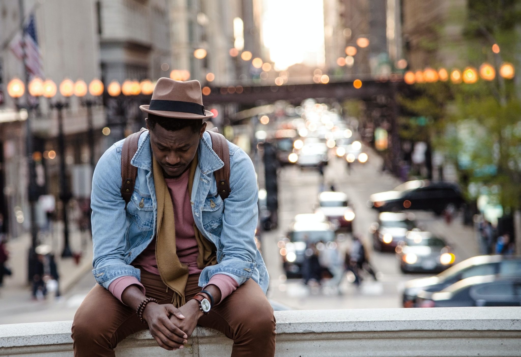 man sitting on wall grieving city background