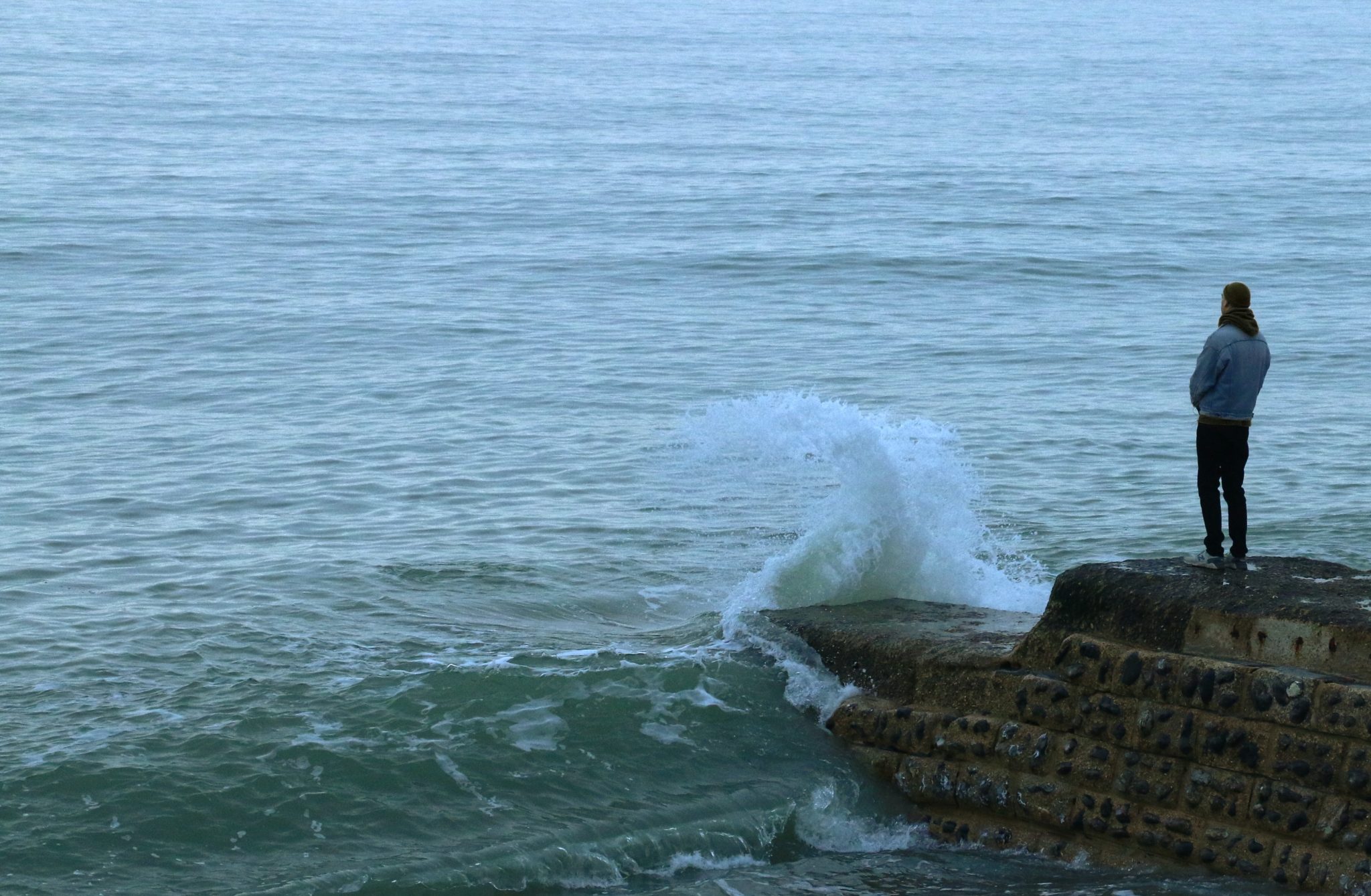 person standing on rocks overlooking ocean