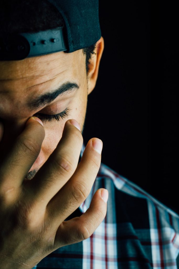 close up of man looking stressed, hand to his face