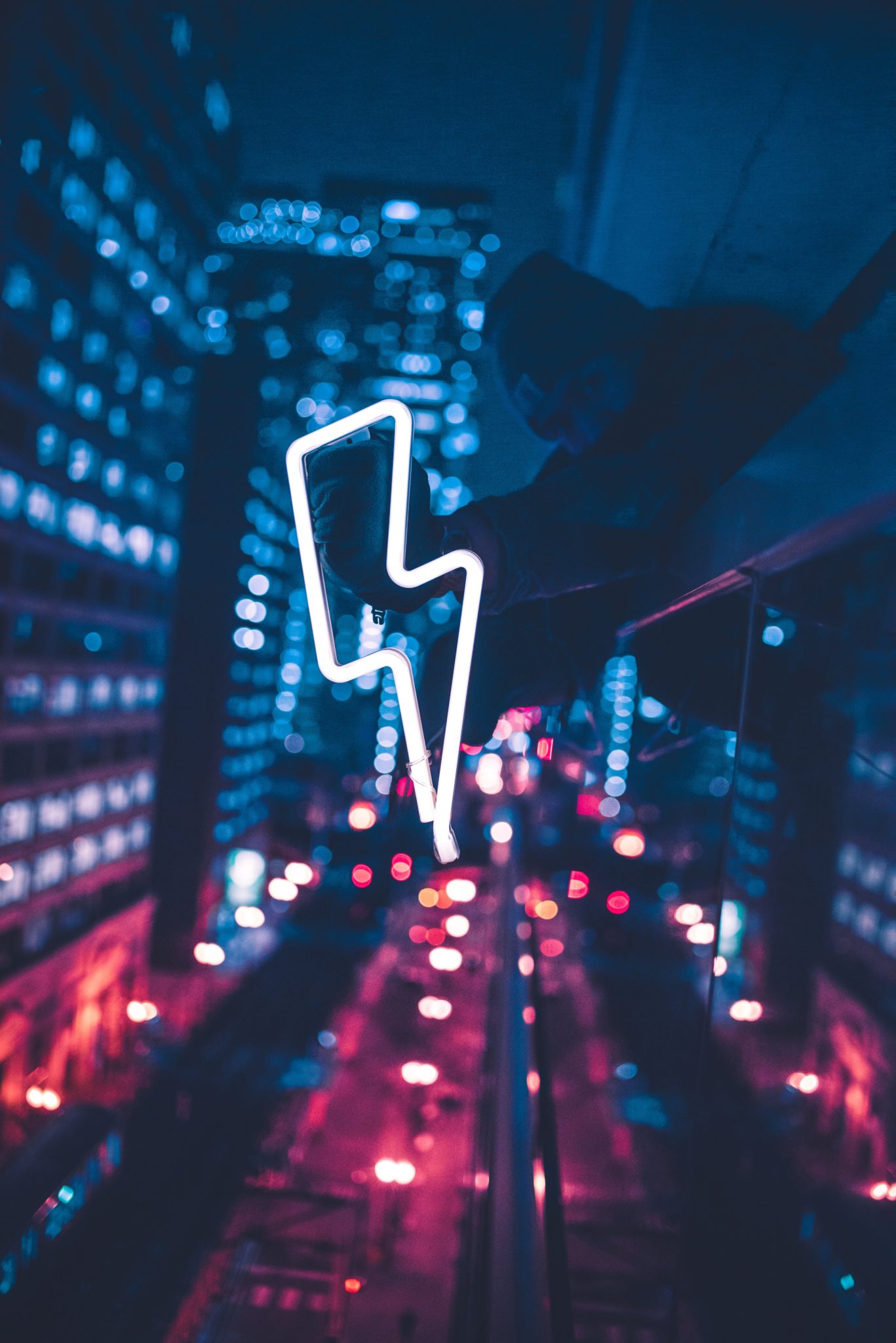 man holding neon lightning sign above the street