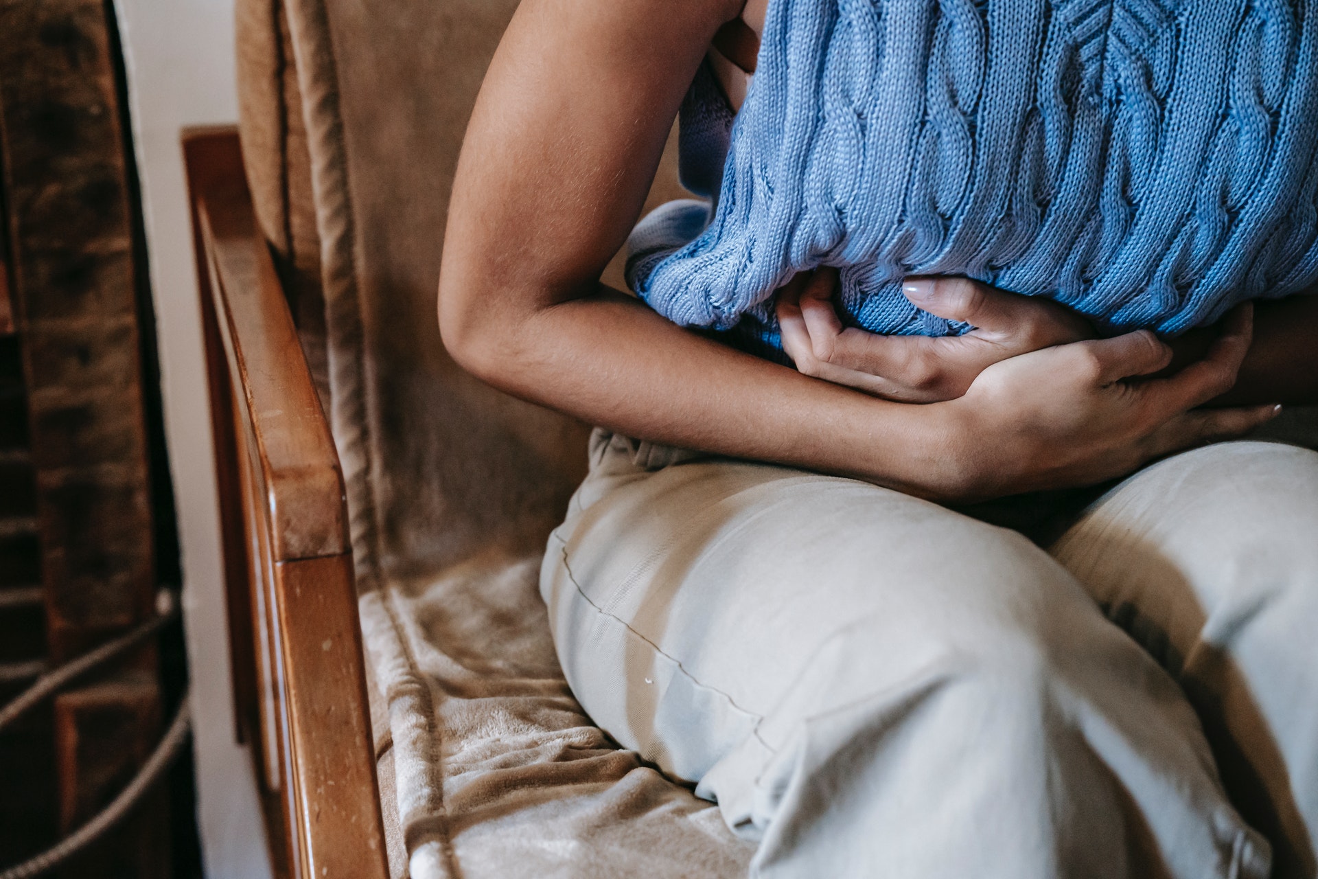 woman in blue sweater clutching stomach